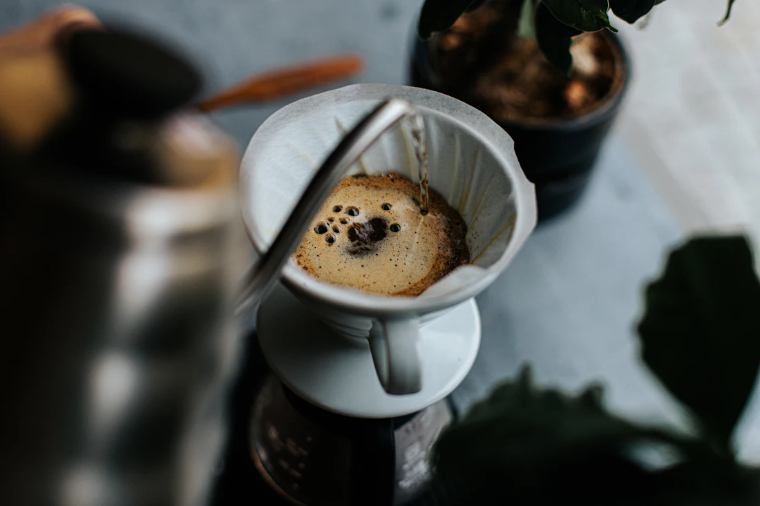 Café preparado en método filtrado goteando dentro de una taza blanca